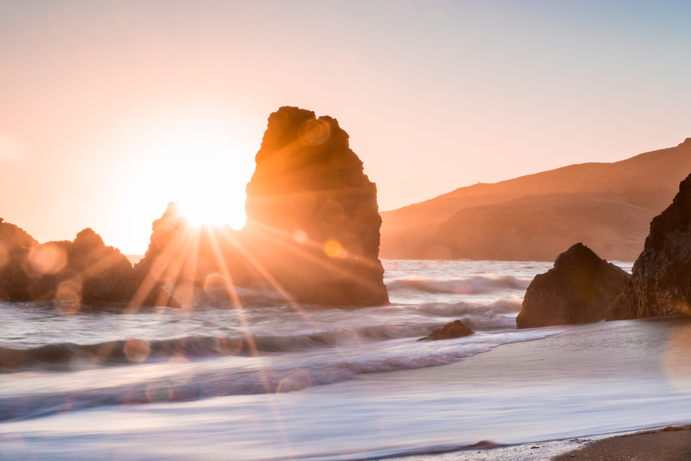 sunrise through ocean rocks